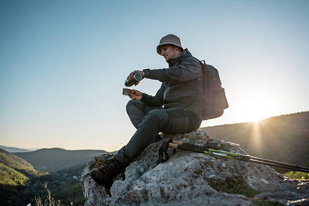istock Hiker Resting on Rock with Sunset While Preparing Drink Outdoors 2212617064
