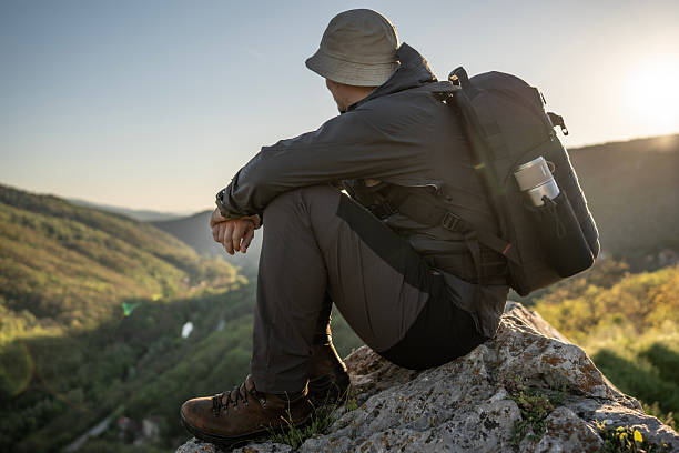istock Man Relaxing Outdoors in Nature With Backpack at Sunrise 2212617089