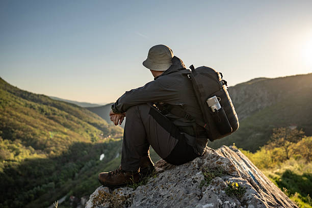 istock Hiker Resting on Mountain Rock Overlooking Scenic Valley During Sunrise 2212617091