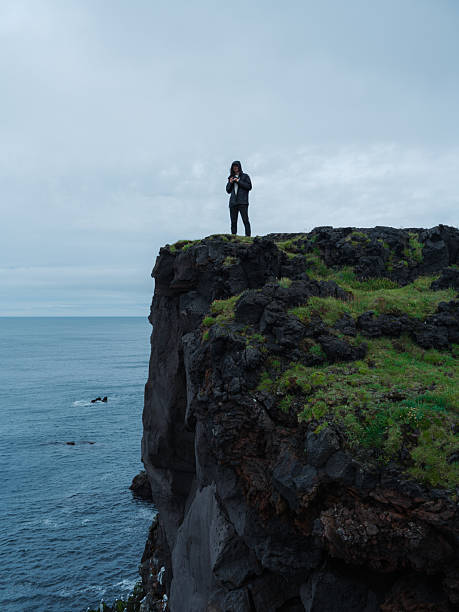 istock Man  standing on the cliff overlooking seaside  in Iceland 2212619189