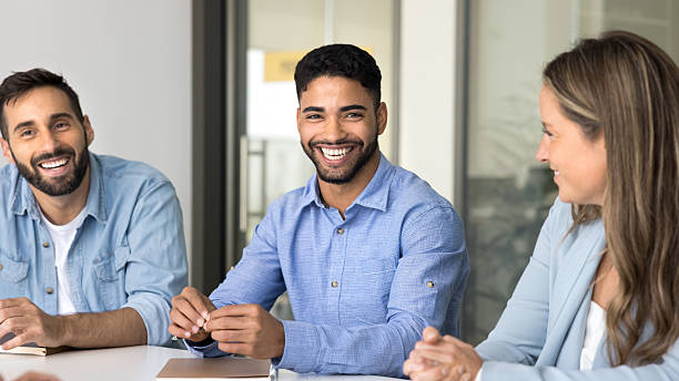 istock Smiling young male manager sit at conference table with teammates 2212622124