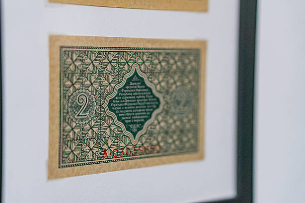Historical, aged Ukrainian banknote pasted on a surface Features a portrait and intricate patterns in blues, greens, purples, and yellows Shows both left and right sides with 3D effect under natura