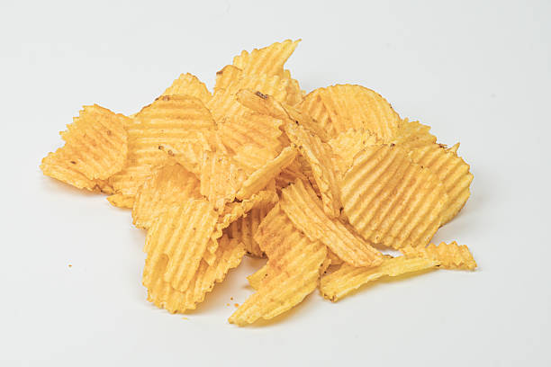 istock Brightly lit, golden-yellow potato chips scattered on a flat surface, with visible ridges and soft shadows. 2212622649
