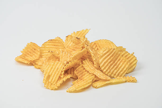 istock Light gray surface with scattered golden-yellow potato chips of varying sizes Indoor setting, artificial lighting. 2212622844