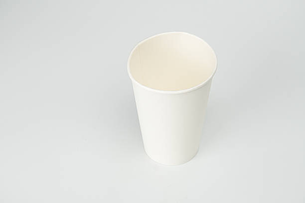 istock A single white paper cup sits on a flat surface, empty with the rim visible Soft, even lighting suggests an indoor setting The image has a simple composition, focusing on the central cup with no ad 2212624733