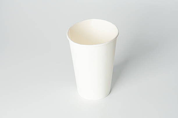 istock Angled view of a textured white and yellow cup on a light gray surface against a blurred backdrop, showcasing minimalist style. 2212624809