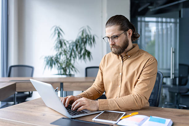 istock Focused businessman working on laptop in modern open-plan office environment 2212624996