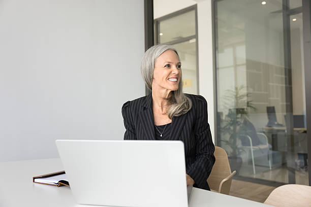 istock Smiling mature businesswoman visualize success sitting by notebook at workplace 2212628108