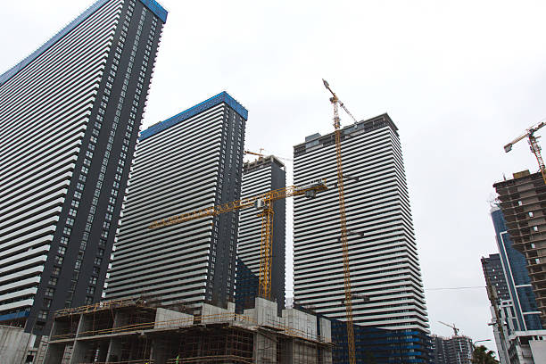 Urban construction cranes high up against the backlight of the urban skyline