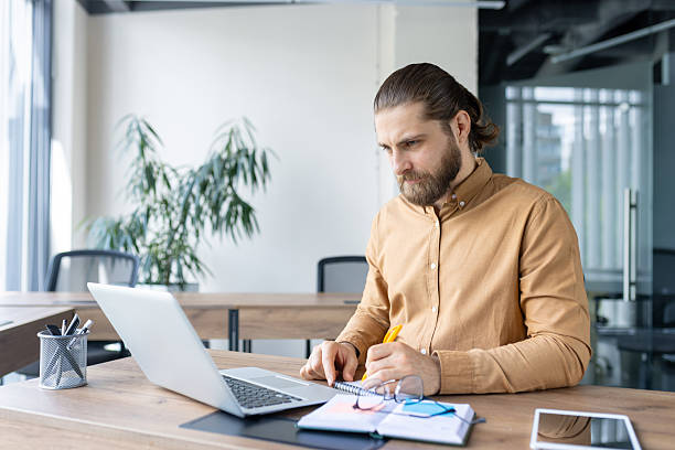 istock Focused professional working on laptop at a modern office workspace 2212633013