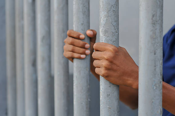 istock hands of prisoners behind bars 2212634994