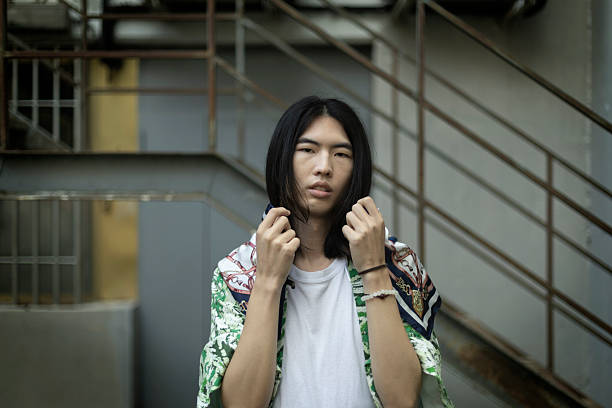 Fashionable young man with long hair posing in an urban environment, showcasing modern streetwear