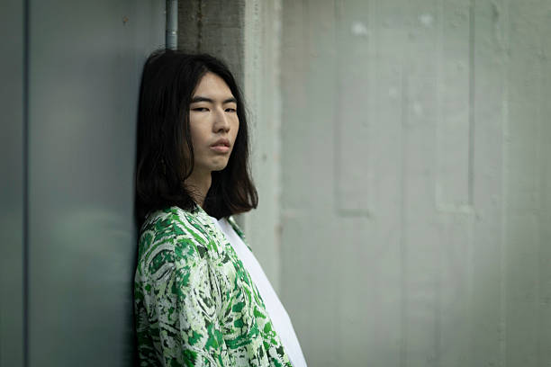 istock Young man with long hair leaning against a wall looking away 2212635645