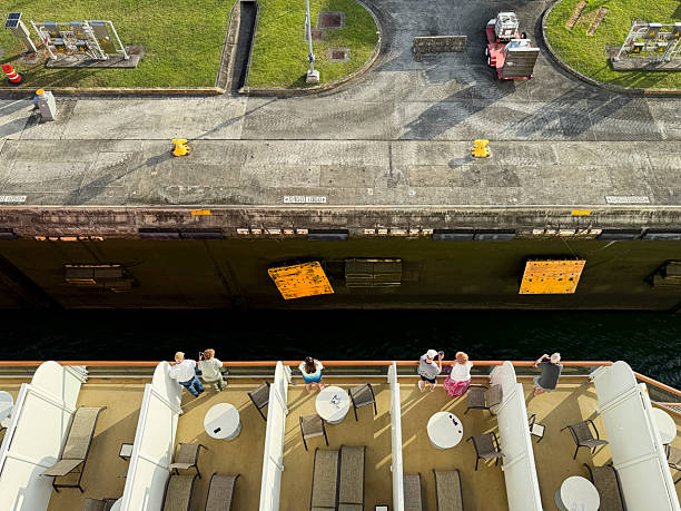 Panama City, Panama - February 17, 2025: Cruise passengers watch from their balconies as their ship enters a lock of the Panama Canal. Due to the size of this ship, it must use the new canal which can accomodate ships up to 1,200 feet long, 168 feet wide, and 47 feet deep.