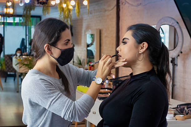 istock Make-up artist applying lipstick on a client in beauty salon 2212638323