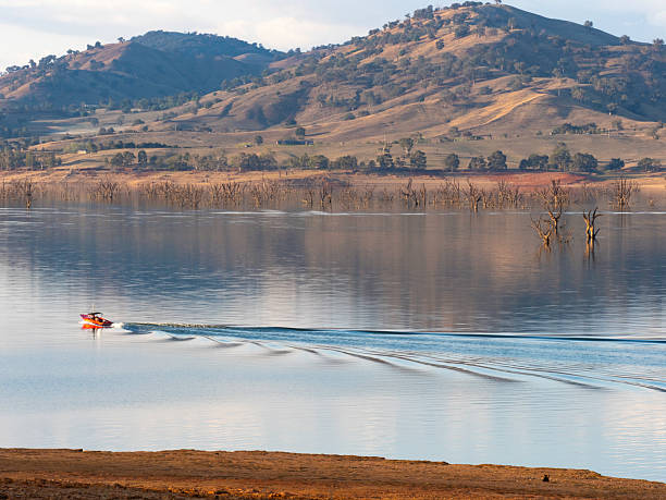 istock Late afternoon light on  on lake, dead trees and speed boat 2212645305
