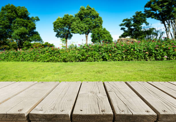 Empty wooden table top with spring garden flowerbed blurred abstract background