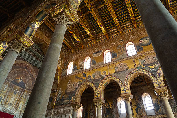 Monreale, Italy - July, 25, 2024: Monreale cathedral, detailed view of cathedral interior featuring intricate mosaics, tall arched columns, large religious artwork behind altar. Biblical scenes