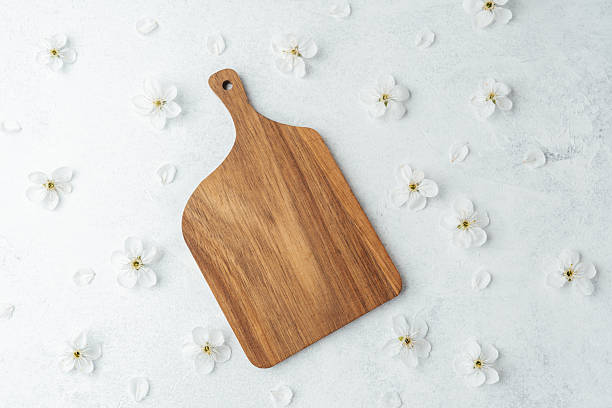 istock Wooden cutting board surrounded by delicate white flowers on a light background 2212649984