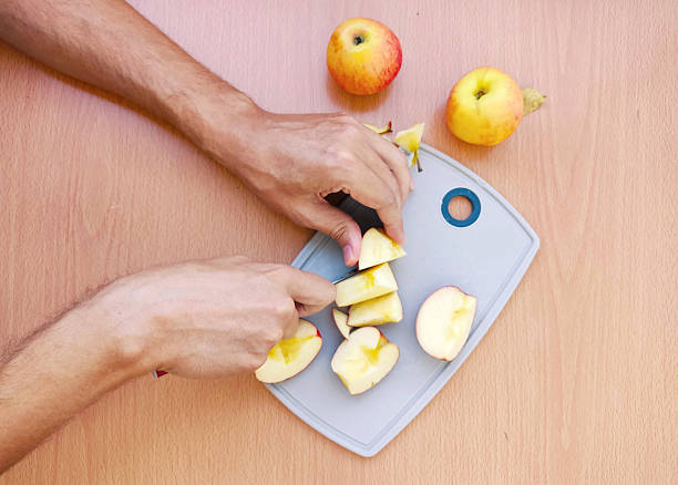 istock Mans hands slicing fresh apples on a cutting board, topdown view. Healthy eating concept. Use for blogs, recipes, wellness articles, or foodrelated websites. 2212650140