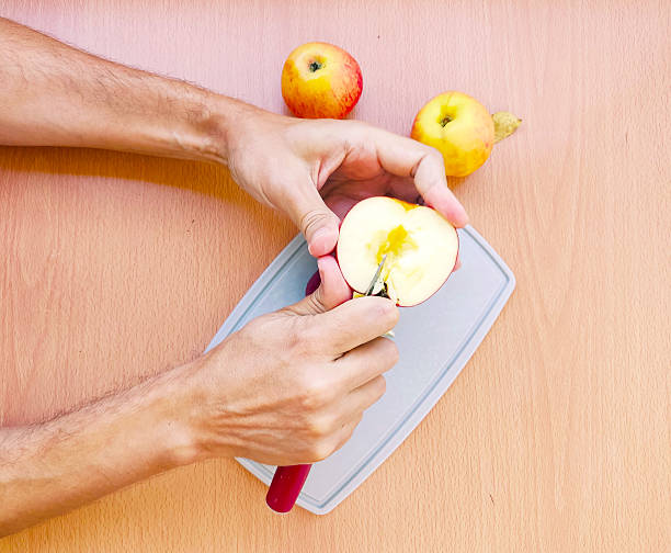 istock Hands coring a fresh apple with a tool. Healthy eating, food preparation, and kitchen concepts. Suitable for blogs, recipes, or health and wellness content. 2212650141