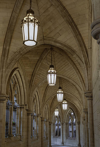 London, UK - Apr 27, 2025 - Cloister arch perspective and Corridor with Antique lantern hanging from ceiling inside of entrance to St Mary Abbots Church. An arched hallway with atmospheric and unusual, vaulted cloistral, use it as your Wallpaper, Poster and Space for text, Selective focus.