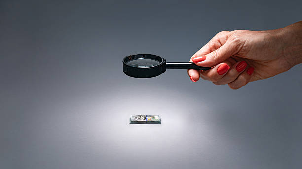 Visual of financial audit using magnifying glass to check expenses and income