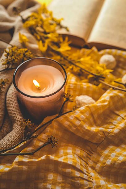 istock A cozy lit candle surrounded by yellow flowers, soft checkered fabric, and an open book, creating a warm and peaceful springtime atmosphere in soft natural light 2212658493
