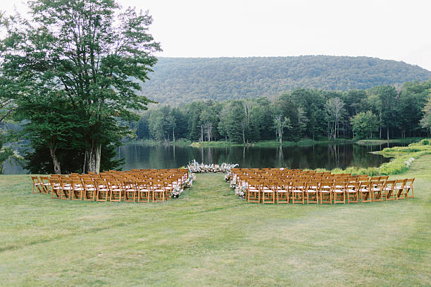 istock wedding ceremony setup by pond with wooden chairs 2212661356