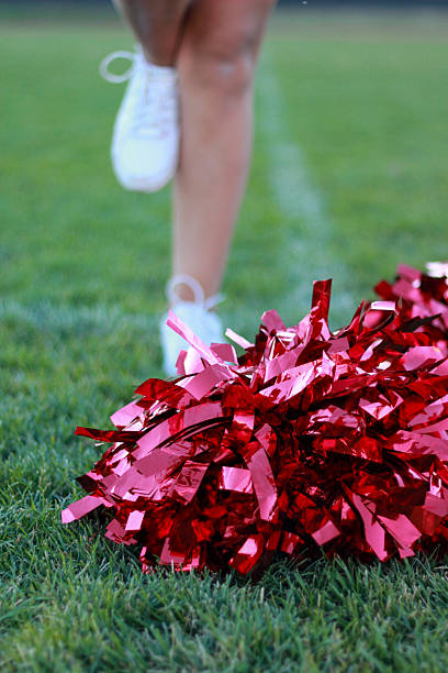 istock Red pom-poms on grass with cheerleader in background 2212661693