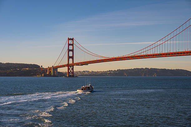 The iconic Golden Gate Bridge in San Francisco, California, with a boat cruising through the bay. This stunning view captures the world-famous suspension bridge, deep blue waters, and the beauty of the city’s coastline.