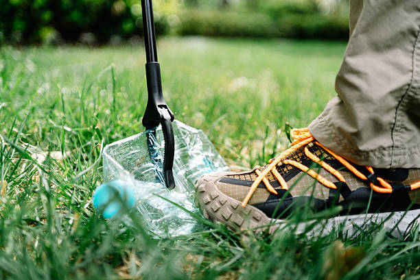 Environmental protection volunteers used tongs to pick up garbage bottles on the ground