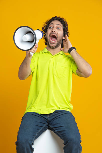 istock Man shouting over megaphone on yellow background 2212671772