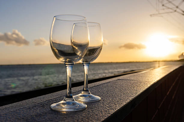 istock Two empty wine glasses resting on a ledge at sunset overlooking the sea 2212672191