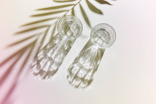 istock Water Glasses with palm leaf Shadow and sunlight Reflection on white background, colored photo minimal style, aesthetic top view summer still life, refraction throug crystal shine cups, caustic 2212672408