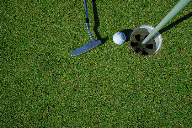 istock Top view of a golf ball with putter on green course at hole. 2212677854