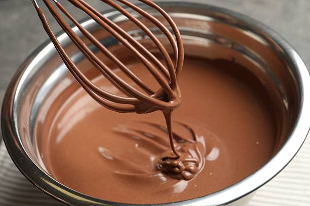 istock Chocolate dough dripping from whisk into bowl on table, closeup 2212678734