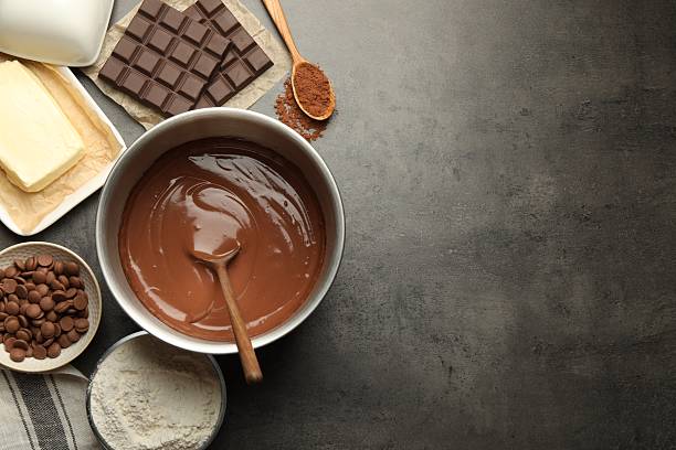 Chocolate dough in bowl and ingredients on grey table, flat lay. Space for text