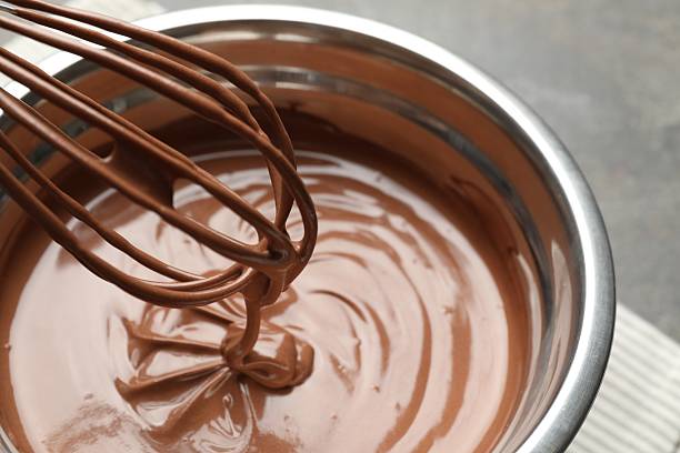 istock Chocolate dough dripping from whisk into bowl on table, closeup 2212678773
