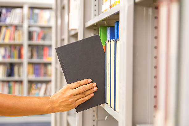 istock Book and library, Close up hand choosing and picking books from bookshelf in library. Concepts of reading textbook and school for student knowledge education or study and learning 2212683933