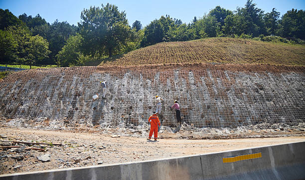 Strengthening of slopes by workers, reinforcement. Protection from falling rocks and minerals on the road. Mesh and piles Kutaisi, Georgia. - August 8, 2024: Strengthening of slopes by workers, reinforcement. Protection from falling rocks and minerals on the road. Mesh and piles https://www.argentium.in/blogs/what-is-slope-stabilization-and-its-methods/ stock pictures, royalty-free photos  images