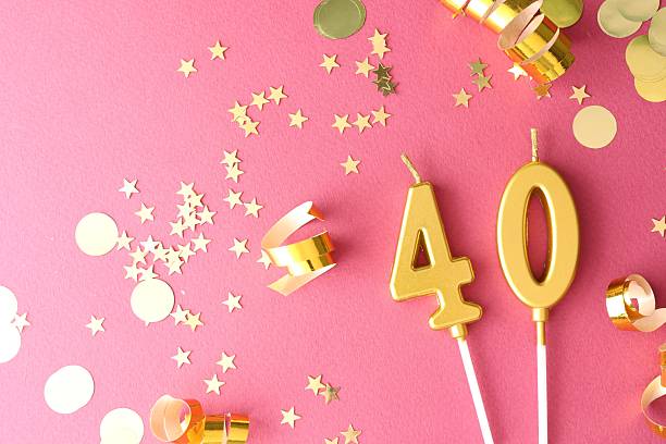 istock 40th birthday. Number shaped candles and confetti on pink background, flat lay 2212687787