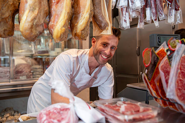istock Butcher smiling while preparing meat in butcher shop 2212688254