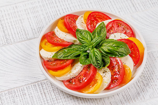 A vibrant and appetizing display of Caprese antipasti featuring slices of ripe garden tomatoes, fresh mozzarella, and aromatic basil leaves