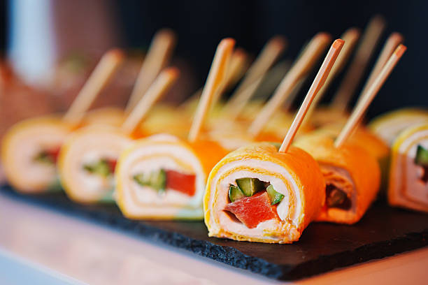 Colorful sushi rolls displayed on a black platter at a culinary event