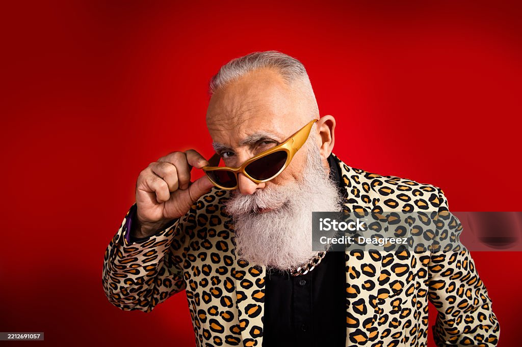 Charismatic mature man in leopard print jacket posing confidently in stylish eyewear against bright red background, exuding glamour A stylish senior with a vibrant leopard print suit and golden sunglasses poses against a red backdrop, radiating charm and individuality. 55-59 Years Stock Photo Charismatic mature man in leopard print jacket posing confidently in stylish eyewear against bright red background, exuding glamour A stylish senior with a vibrant leopard print suit and golden sunglasses poses against a red backdrop, radiating charm and individuality. 55-59 Years Stock Photo