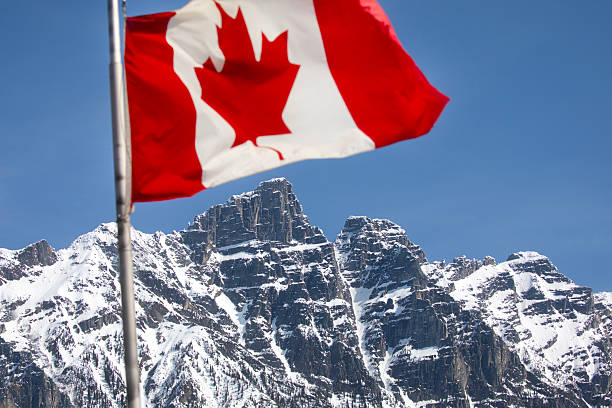 istock Canadian flag  and snow capped mountains 2212691156