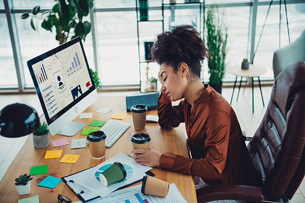 istock Young businesswoman experiencing workplace challenges at a modern office desk with visible data charts, paper work 2212693376