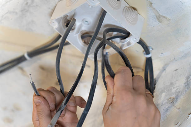 istock Electrician carefully connecting electrical wires to a junction box on a ceiling during a home renovation, ensuring safe and reliable electrical connections 2212693417