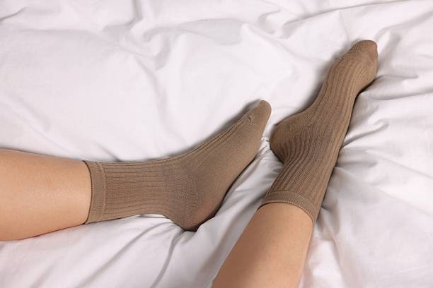 istock Woman wearing light brown socks on bed, above view 2212693809